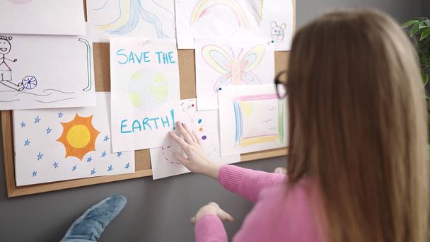 Giovane donna bionda che lavora come insegnante appeso salvare la terra disegnare su sughero all'asilo - Foto, immagini