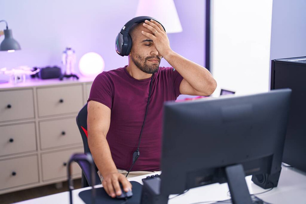 Young latin man streamer stressed using computer at gaming room - Фото, изображение