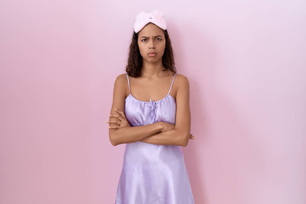 Young hispanic woman wearing sleep mask and nightgown skeptic and nervous, disapproving expression on face with crossed arms. negative person.  - Foto, Imagen