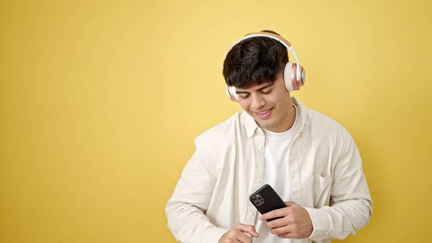 Νεαρός Ισπανόφωνος ακούγοντας μουσική να χορεύει πάνω σε απομονωμένο κίτρινο φόντο - Φωτογραφία, εικόνα