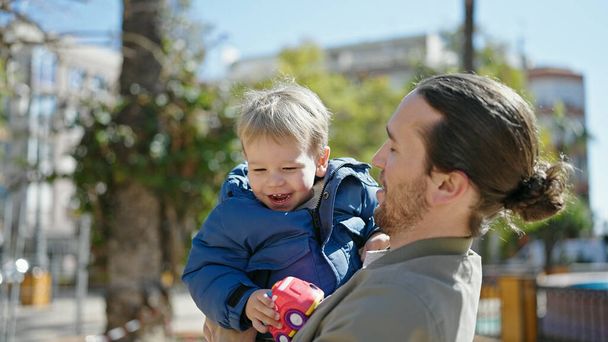 Otec a syn se usmívají a objímají se v parku. - Fotografie, Obrázek
