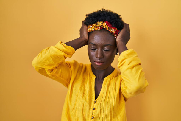 Africká mladá žena nosí africký turban trpí bolestí hlavy zoufalé a vystresované, protože bolest a migréna. Ruce za hlavu.  - Fotografie, Obrázek