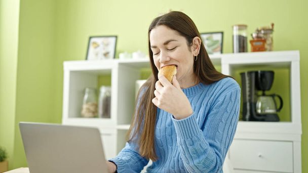 Young caucasian woman using laptop having breakfast at dinning room - Foto, Bild