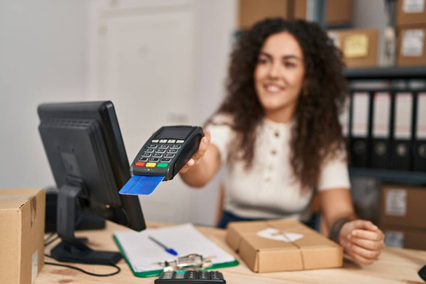 Młoda piękna latynoska kobieta e-commerce pracownik za pomocą telefonu danych i karty kredytowej w biurze - Zdjęcie, obraz