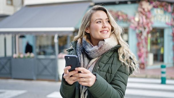 Young blonde woman smiling confident using smartphone at coffee shop terrace - Fotografie, Obrázek