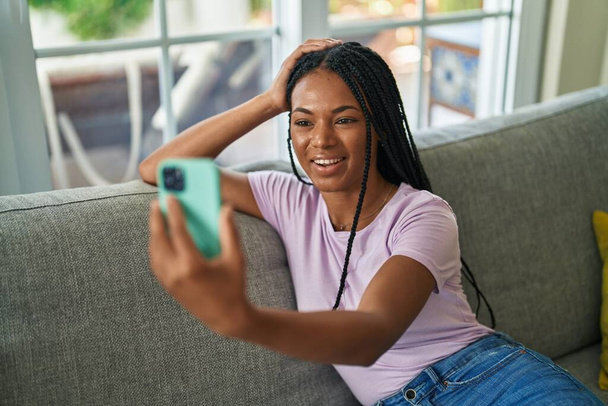 アフリカ系アメリカ人の女性がビデオ通話を持っていますソファに家に座って - 写真・画像