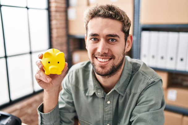 Young man ecommerce business worker holding piggy bank at office - Foto, Bild