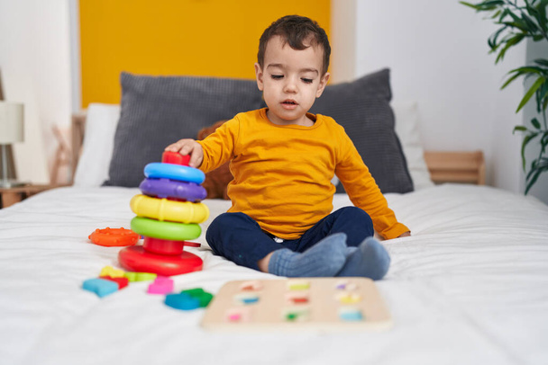 Adorable hispanic boy playing with hoops game sitting on bed at bedroom - Photo, Image