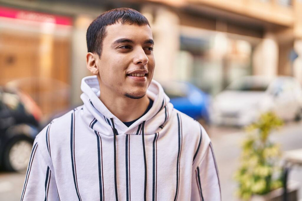 Молодой человек улыбается уверенно стоя на улице - Фото, изображение
