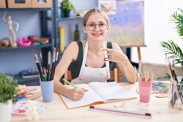 mujer rubia joven dibujando en el estudio de arte  - Foto, imagen