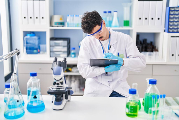 Young caucasian man scientist writing report working at laboratory - Photo, Image
