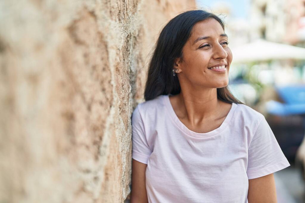 Young beautiful hispanic woman smiling confident looking to the side at street - Fotoğraf, Görsel