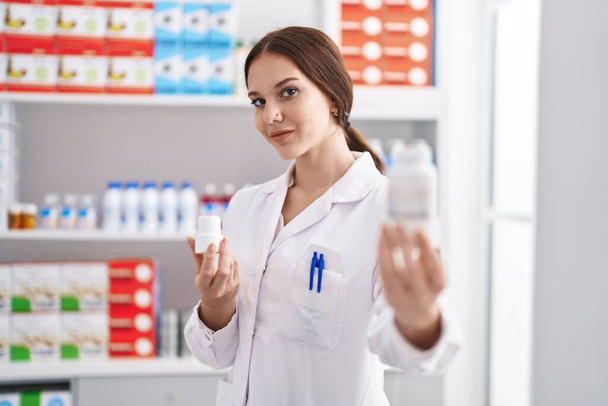 Fiatal nő gyógyszerész gazdaság tabletták palack gyógyszertár - Fotó, kép