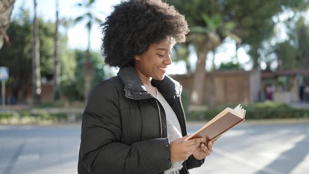 Mujer afroamericana sonriendo confiado libro de lectura en la calle - Foto, Imagen