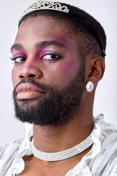 male princess in crown and elegant white outfit posing looking pretty, feminine transgender transvestite. attractive guy of black american ethnicity with make-up comsetics on face. beauty - Photo, image