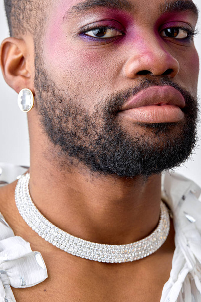 close-up portrait of black young man with pink eyeshadow make-up, look at camera. black american feminine womanlike guy is modern, stylish, self-confident. models, beauty, fashion concept - Foto, Bild