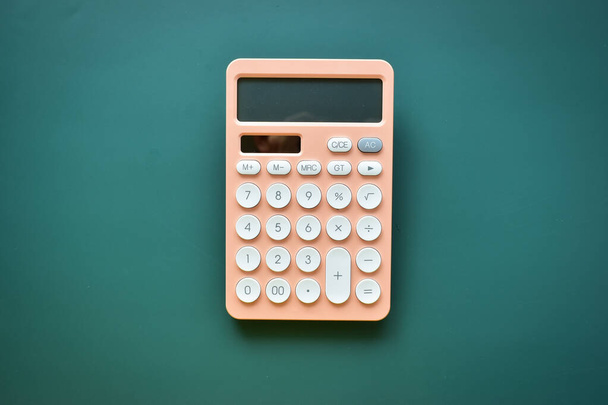 moderner pfirsichfarbener Pastell-Taschenrechner und weiße Taste auf grünem Hintergrund, Geschäfts- und Finanzbuchhaltungskonzept - Foto, Bild