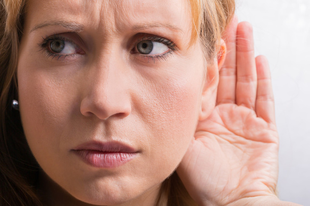 Mujer preocupada escuchando con la mano en la oreja
 - Foto, Imagen
