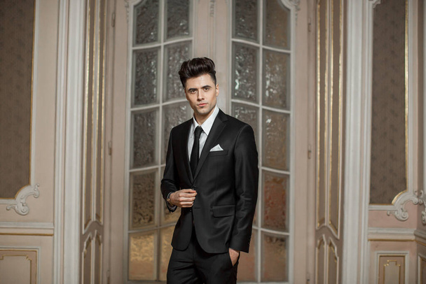 Przystojny mężczyzna model w nowym garniturze w pięknym pokoju - Zdjęcie, obraz