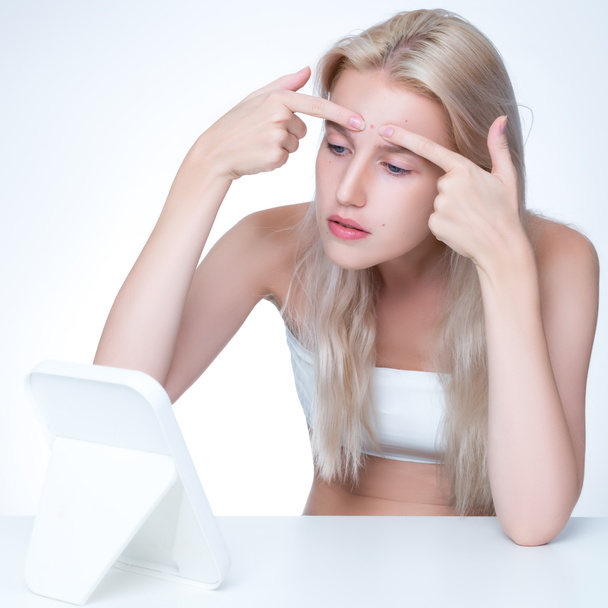Acne problem troubling personable worried woman with natural beauty skin checking her face squeezing pimple spots in isolated background. Copyspace for blemish skincare treatment problem. - Foto, imagen