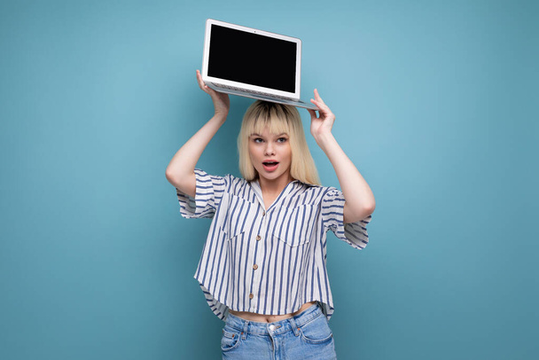 exitosa mujer joven rubia independiente con camisa a rayas que muestra el anuncio en el ordenador portátil en el fondo del estudio. - Foto, imagen