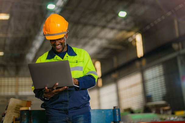 Factory engineer African man standing confidence with laptop. Worker works at heavy machine at industry factory. with machinery equipment plant technology. - Zdjęcie, obraz