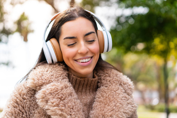 Nuori brunette nainen ulkona kuuntelemassa musiikkia - Valokuva, kuva