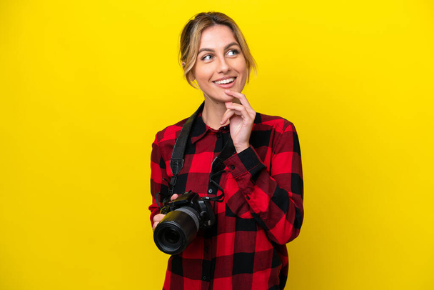 Femme photographe uruguayenne isolée sur fond jaune penser une idée tout en levant les yeux - Photo, image