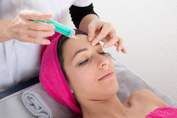 vrouw krijgt een injectie in haar gezicht - Foto, afbeelding