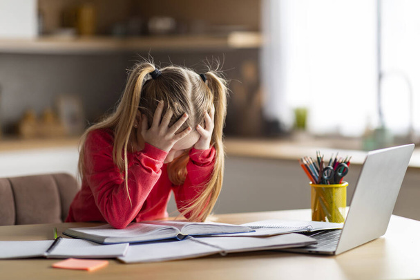 Dyslexie Concept. Meisje worstelend met huiswerk, gestresste peuter vrouwelijk kind met leesproblemen, zitten aan de balie thuis, kijken naar boek en raken hoofd met wanhoop, kopiëren ruimte - Foto, afbeelding