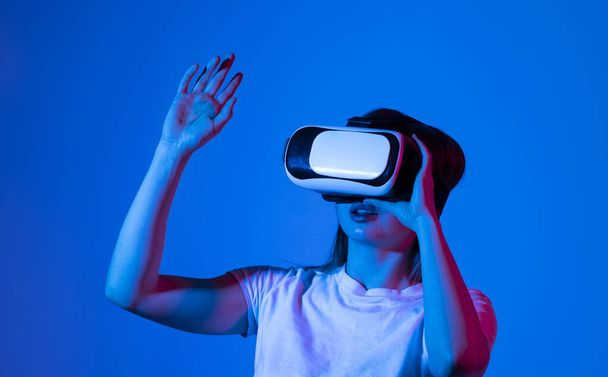 Close up of young woman stands in studio wearing VR glasses and swiping scrolling zooming with hands in a virtual space while interacting with a objects in a metaverse. Virtual reality technology - Fotoğraf, Görsel