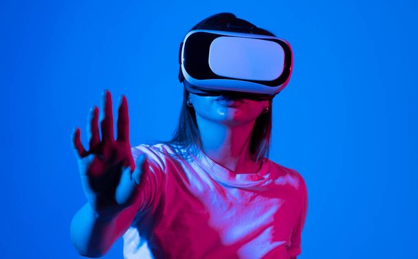 Brunette woman with VR headset touching something what she see in virtual world. Futuristic technology - Valokuva, kuva
