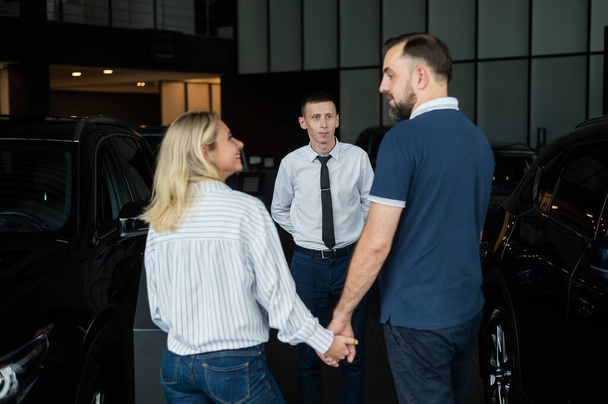 Happy caucasian couple choosing a new car in a car dealership - Zdjęcie, obraz