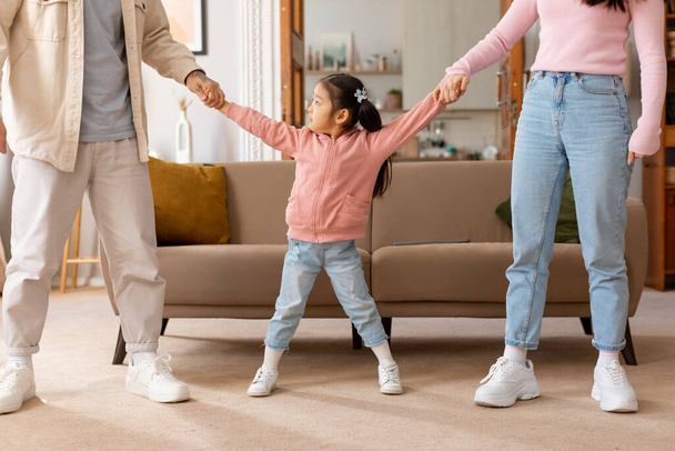 Cropped Shot Of Asian Little Girl Holding Hands With Her Parents And Looking Up Sadly At Dad, Waiting For His Attention And Support Posing At Home. Parents And Child Relationship Issue - Foto, Bild