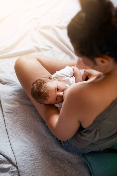 La lactancia materna tiene muchos beneficios. Foto de ángulo alto de una madre joven amamantando a su bebé recién nacido en casa - Foto, imagen