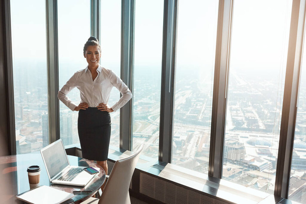 La parte superiore e 'il suo posto. una giovane donna d'affari attraente in piedi con le mani sui fianchi in ufficio - Foto, immagini