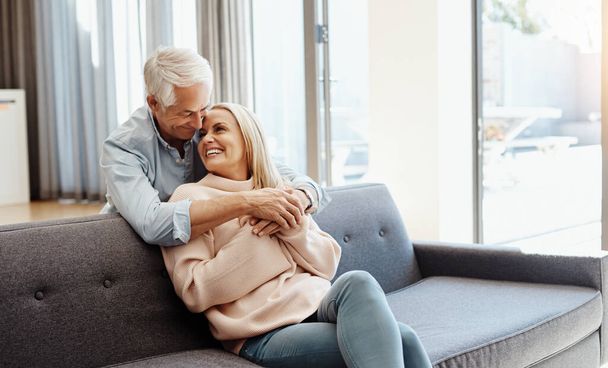 Rakkaus tekee onnellisen kodin. kypsä mies halaa vaimoaan sohvalla kotona - Valokuva, kuva