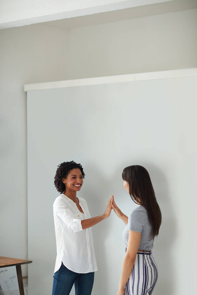 I couldnt have done it without your help. two young businesswomen giving each other a high five in a modern office - 写真・画像