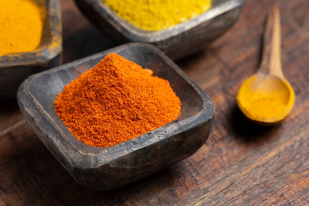 Turmeric, pepper and curry powder in container on wooden background - Φωτογραφία, εικόνα