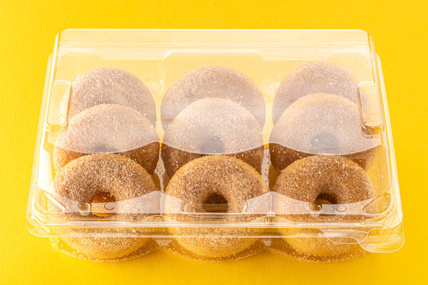 Donuts or  Doughnuts with sugar in transparent plastic box for sale on yellow background - Zdjęcie, obraz
