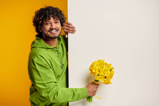 Handsome Indian man holding bouquet of flowers against colorful background - Photo, Image