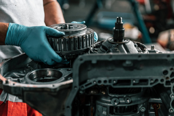 Auto mechanic diagnose and troubleshoots with tools and equipment. Polishing car, fixing braking and steering systems. Measuring oil levels with oil gauge stick and then pouring or changing it. - 写真・画像