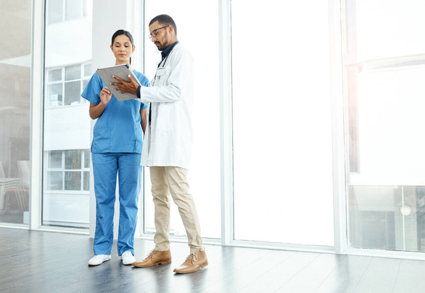 Sie tun es, um etwas zu bewirken. zwei junge Ärzte mit einem digitalen Tablet in einem modernen Krankenhaus - Foto, Bild