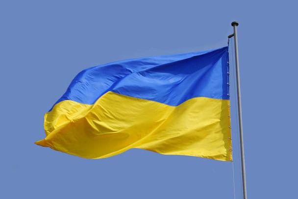 Ukraińska flaga na błękitnym niebie. Flaga, symbol państwa ukraińskiego, trzepocze na wietrze. - Zdjęcie, obraz