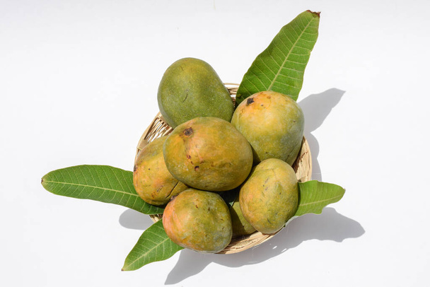 Saftige Mangos und Mangoblätter im Korb auf weißem Hintergrund - Foto, Bild