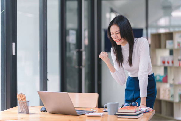 Happy and excited, a young asian woman student or office worker, celebrates achieving her goal of winning an online competition or receiving good news via email by raising hands in euphoria - Foto, immagini