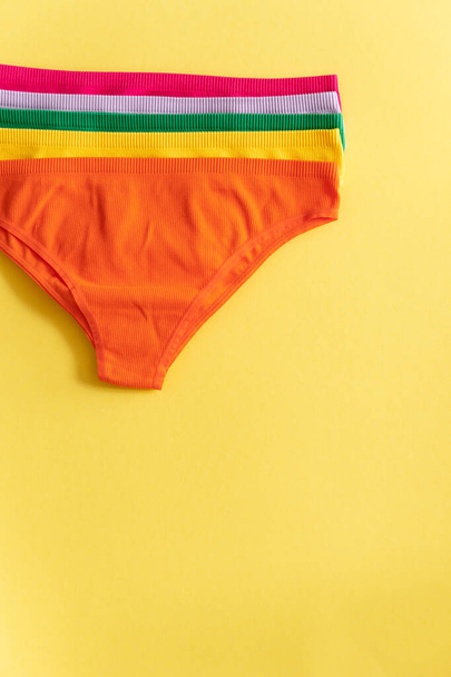 Värikkäitä alushousuja keltaisella pohjalla, lähikuva. Puuvillapikkuhousut. Naisten alusvaatteet. Yläkuva - Valokuva, kuva