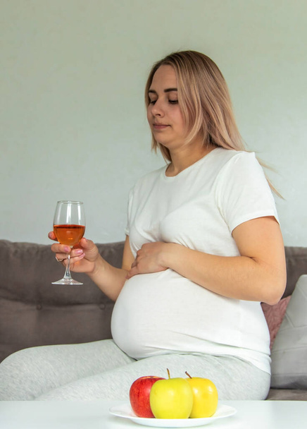 Беременная женщина пьет вино в стакане. Выборочный фокус. Еда. - Фото, изображение