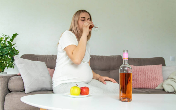 A pregnant woman drinks wine in a glass. Selective focus. Food. - Zdjęcie, obraz