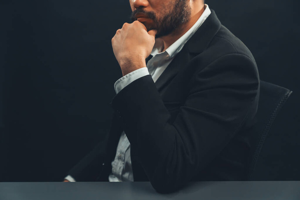 Бизнесмен или юрист в формальном черном костюме сидит за столом на изолированном черном фоне. Концепция человека с авторитетом и жестом серьезности. Равновесие - Фото, изображение